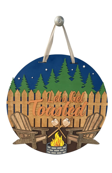 Let's Get Toasted camping door hanger with Adirondack chairs, campfire, and pine tree background.